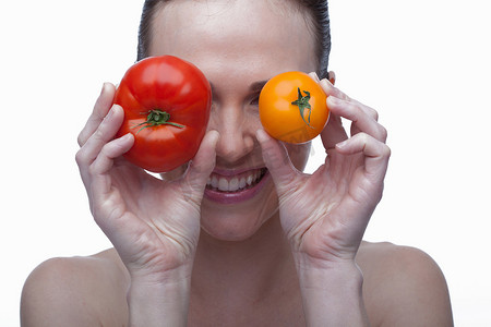 一名年轻女子用红黄相间的西红柿遮住眼睛