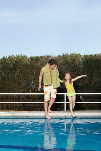 父亲和女孩在泳池里摸脚趾