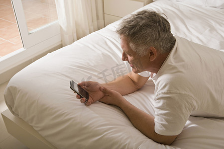 在床上使用智能手机的成熟男人