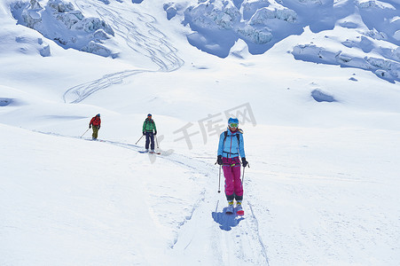一排三名成年滑雪者沿着法国格拉尼亚阿尔卑斯山的勃朗峰滑雪