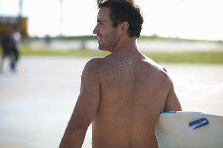 美国加利福尼亚州威尼斯海滩男性冲浪者背着冲浪板的背影