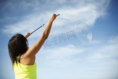 女人的后视线用泡泡魔杖举起手臂制造泡泡