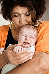 哭泣摄影照片_奶奶抱着哭闹的婴儿