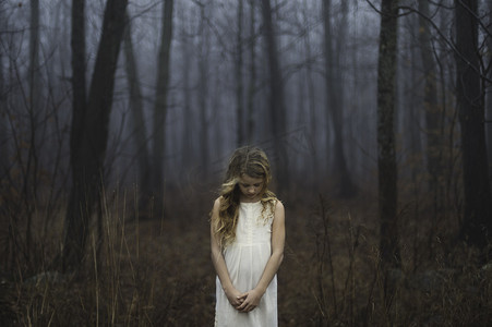 至低摄影照片_雾蒙蒙的森林里低着头的金发女孩的肖像