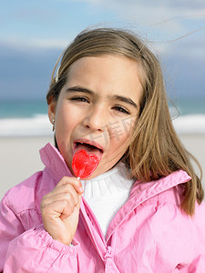 海边拿着棒棒糖的年轻女孩