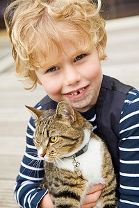 双猫头摄影照片_微笑的男孩在户外抱着猫