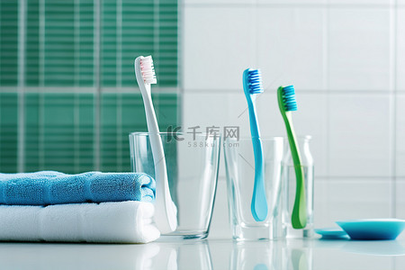 瓷砖背景上玻璃杯中的多支牙刷牙刷用具和毛巾