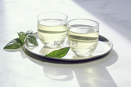 白色大理石盘上放着两杯绿茶和绿叶