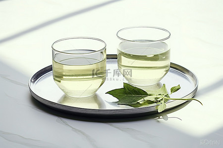 白色大理石盘上放着两杯绿茶和绿叶