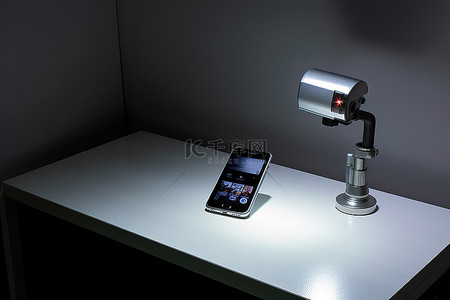 桌子上的手机背景图片_白色桌子上的一部手机和一台闭路电视