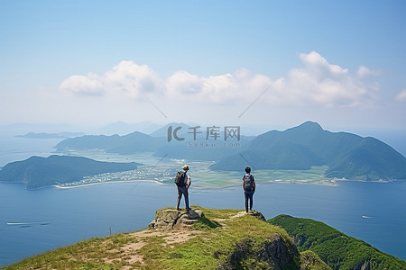 三个人站在山顶观察海洋和山脉
