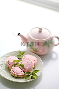 一个茶壶，里面有粉红色的饼干，上面有绿茶叶