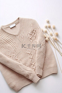 冬天温暖背景图片_一件毛衣和织针放在白色表面上
