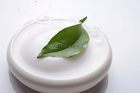一个白色的碗，上面有一片绿叶