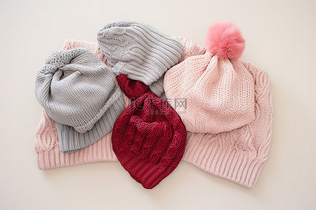 三顶帽子和围巾放在粉红色的心上