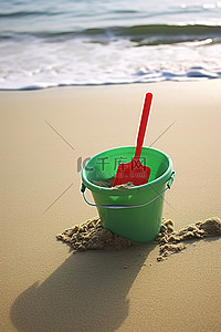玩沙子背景图片_一个绿色的桶，上面有一个红色的勺子，坐在沙子上