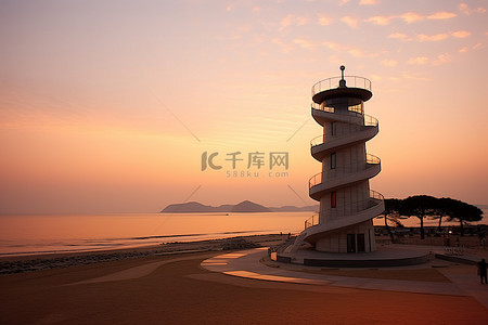 海洋灯塔背景图片_天安海洋灯塔沙滩上的日出