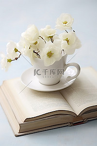 一个白色的杯子，上面有鲜花，旁边坐着一本古书