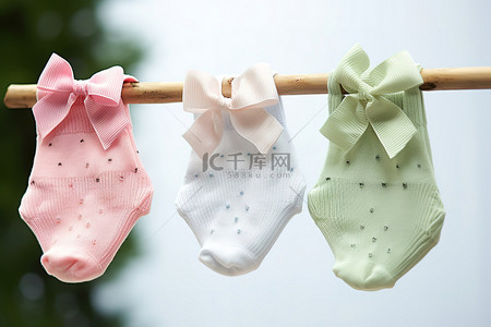 晾衣绳背景图片_三只婴儿脚踝袜挂在晾衣绳上，脚上有蝴蝶结