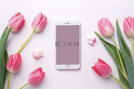 粉色郁金香智能手机放在桌子上，周围是一些花