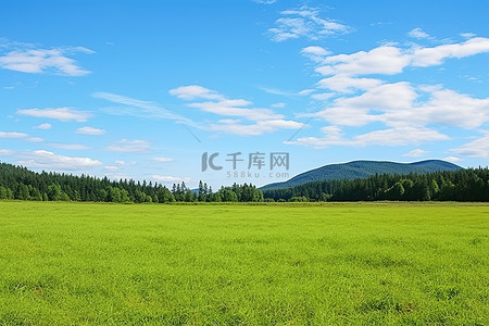 广阔背景图片_广阔的绿色田野，蓝天上周围有群山
