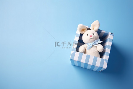 一只玩具兔子坐在蓝色背景的盒子里