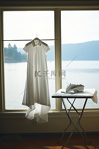 白色的裙子挂在靠近窗户的白色熨衣板上，可以看到风景