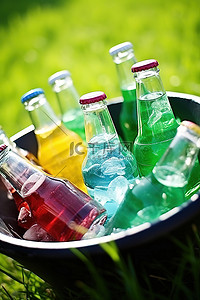 瓶背景图片_绿草旁边的碗里放着彩色饮料瓶