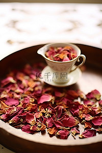 干玫瑰花瓣背景图片_盘子里放着一杯茶，上面有干玫瑰花瓣