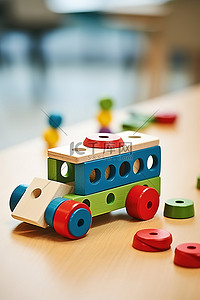 一张桌子，上面摆着五颜六色的木制玩具，旁边停着一辆蓝色的汽车