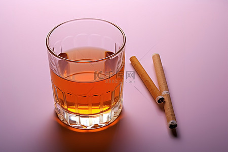 芙蓉王香烟背景图片_一杯装有橙色液体的玻璃杯，旁边有两根香烟