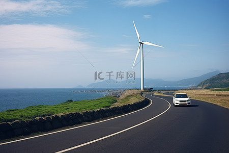 运输背景图片_一辆汽车沿着风力涡轮机附近的道路行驶
