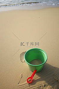 海滩公园沙滩上的一个绿色小塑料碗和一个红色飞溅物