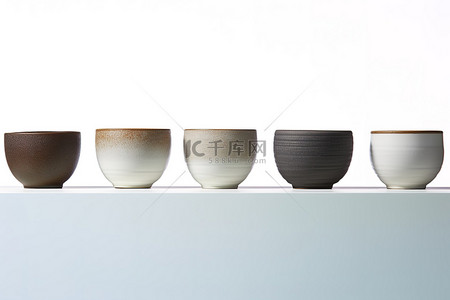 五个白色小陶瓷碗排在玻璃架子的顶排