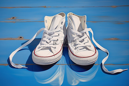 一双白色匡威运动鞋坐在蓝色地板上