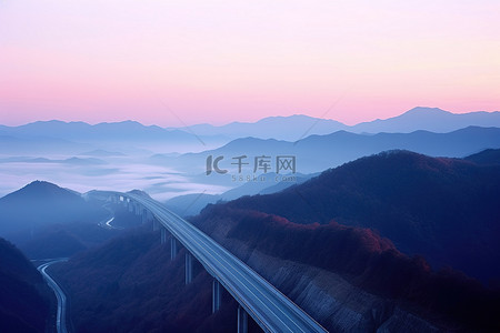 日出时的山景，路上有一座桥