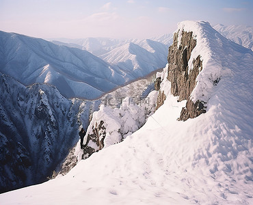 一个男人站在白雪覆盖的悬崖边山旁