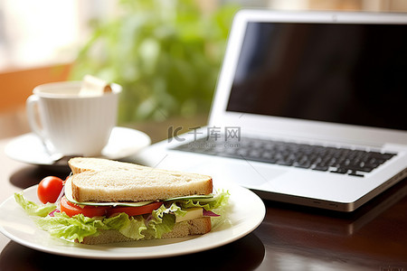 在办公桌上享用午餐和工作 笔记本电脑 三明治和沙拉