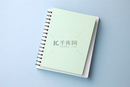 春天日记背景图片_白色表面上的绿色笔记本，带有小白色记事本