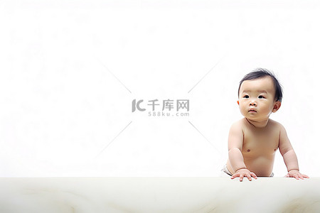 一个婴儿坐在白色画布上抬头看