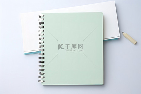 春天日记背景图片_白色表面上的绿色笔记本，带有小白色记事本