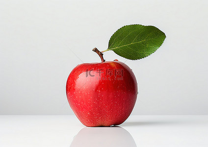 白色桌子上放着一个只有一片叶子的苹果