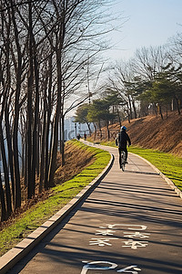 天空路上背景图片_一名男子骑着自行车在穿过韩国公园的小路上
