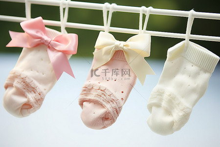 三只婴儿脚踝袜挂在晾衣绳上，脚上有蝴蝶结