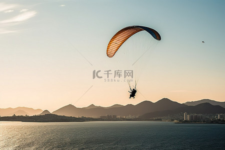 伞背景图片_在海洋附近滑翔伞，背景是山脉