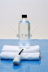 白桌上的水瓶羽毛球篮和羽毛球拍，带蓝色毛巾