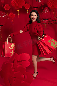 新年购物红色背景下的一位亚洲青年女性拿着购物袋
