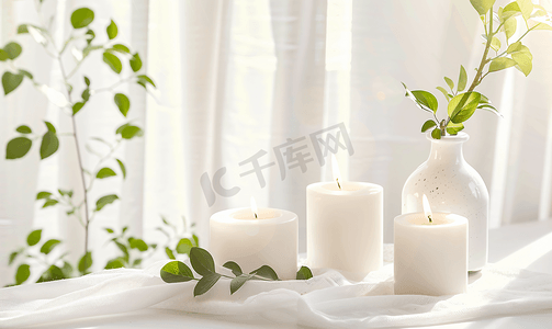 美丽燃烧的蜡烛与绿叶在花瓶在白色桌子