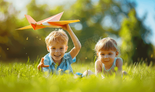 放飞梦想摄影照片_草地上玩纸飞机的孩子们