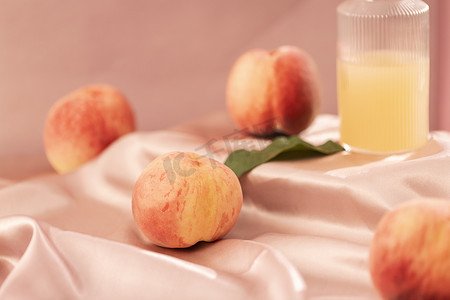 饮料海报摄影照片_鲜榨桃汁与新鲜桃子粉色氛围图